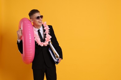 Photo of Businessman with folders, wreath of flowers and inflatable ring on orange background, space for text