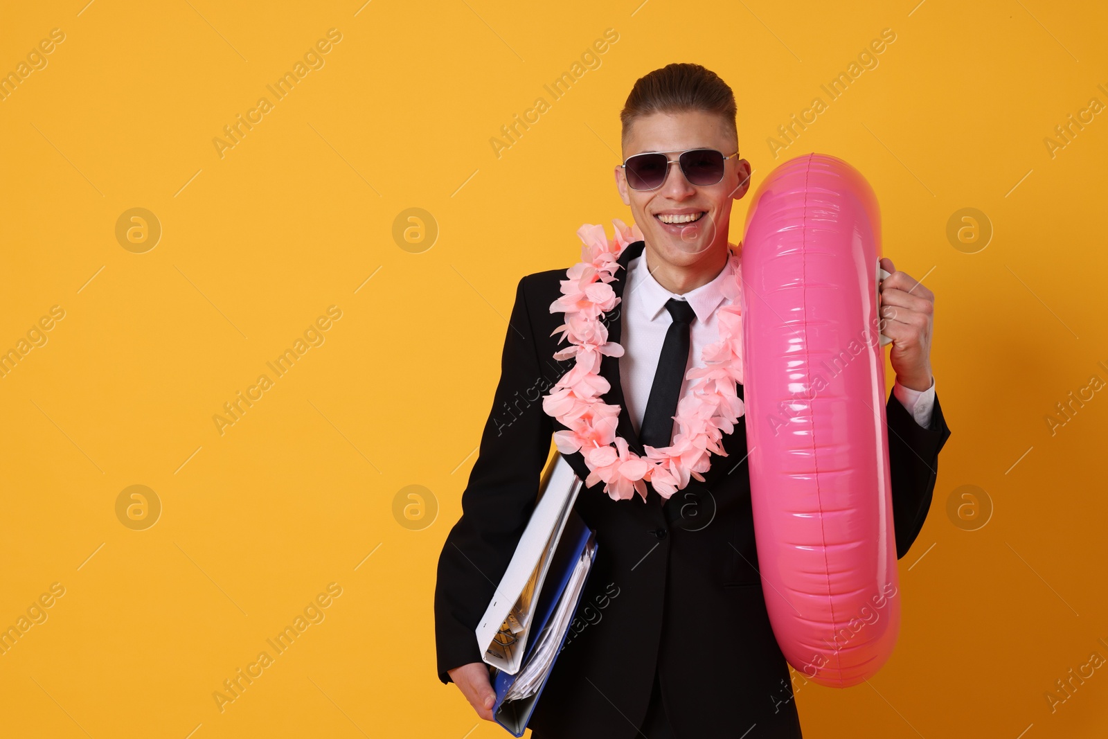 Photo of Businessman with folders, wreath of flowers and inflatable ring on orange background, space for text