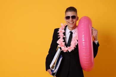 Photo of Businessman with folders, wreath of flowers and inflatable ring on orange background, space for text