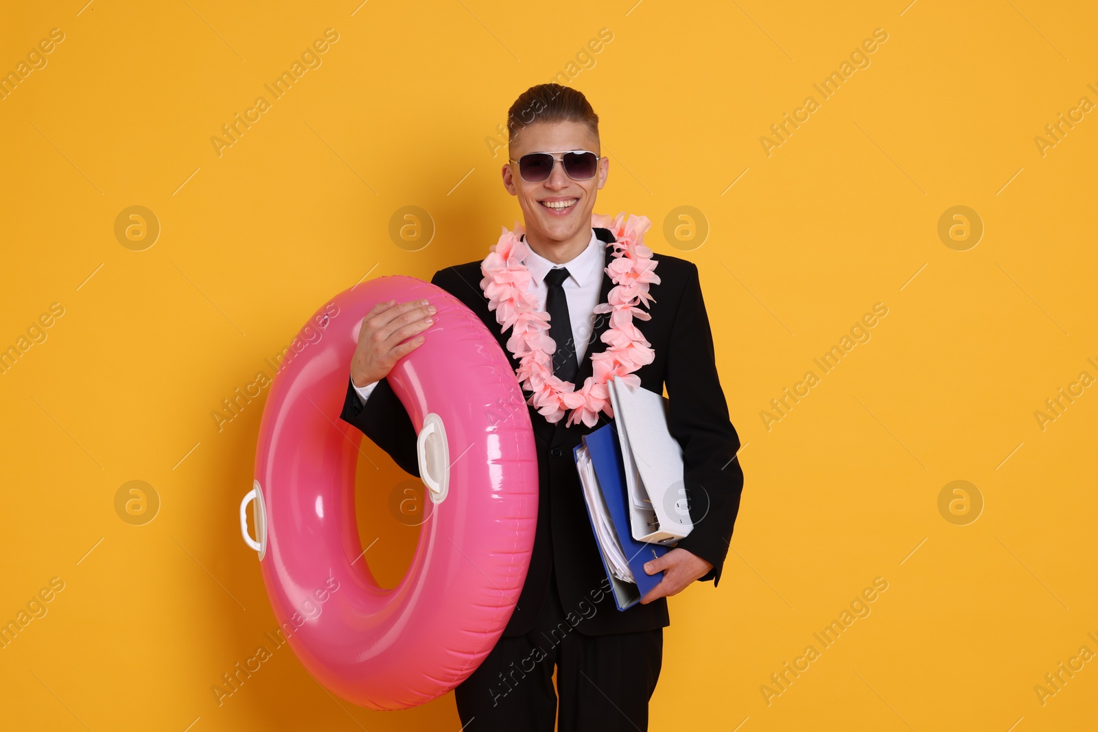 Photo of Businessman with folders, wreath of flowers and inflatable ring on orange background