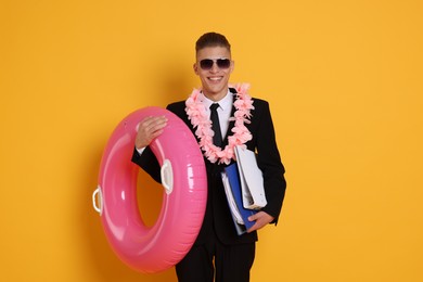 Photo of Businessman with folders, wreath of flowers and inflatable ring on orange background