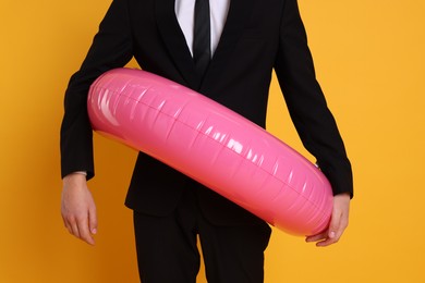 Photo of Businessman with inflatable ring on orange background, closeup