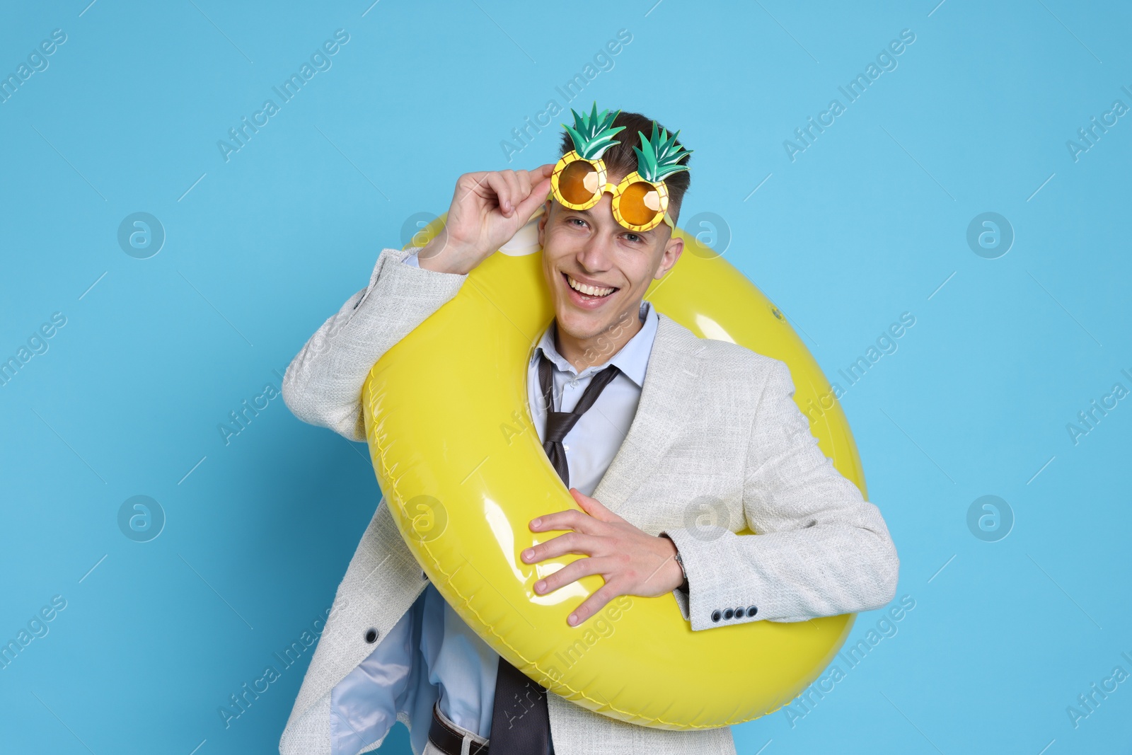 Photo of Businessman with inflatable ring and funny sunglasses on light blue background