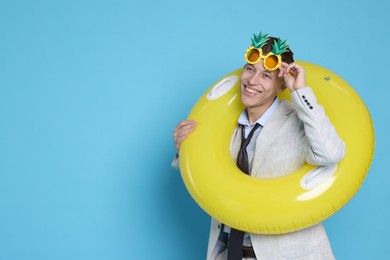 Photo of Businessman with inflatable ring and funny sunglasses on light blue background, space for text