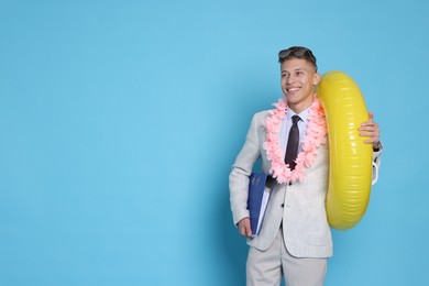 Photo of Businessman with inflatable ring, wreath of flowers and folder on light blue background, space for text