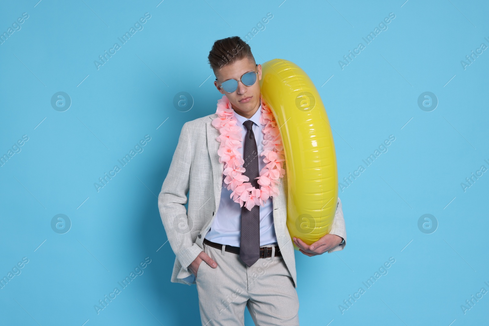 Photo of Businessman with inflatable ring and wreath of flowers on light blue background