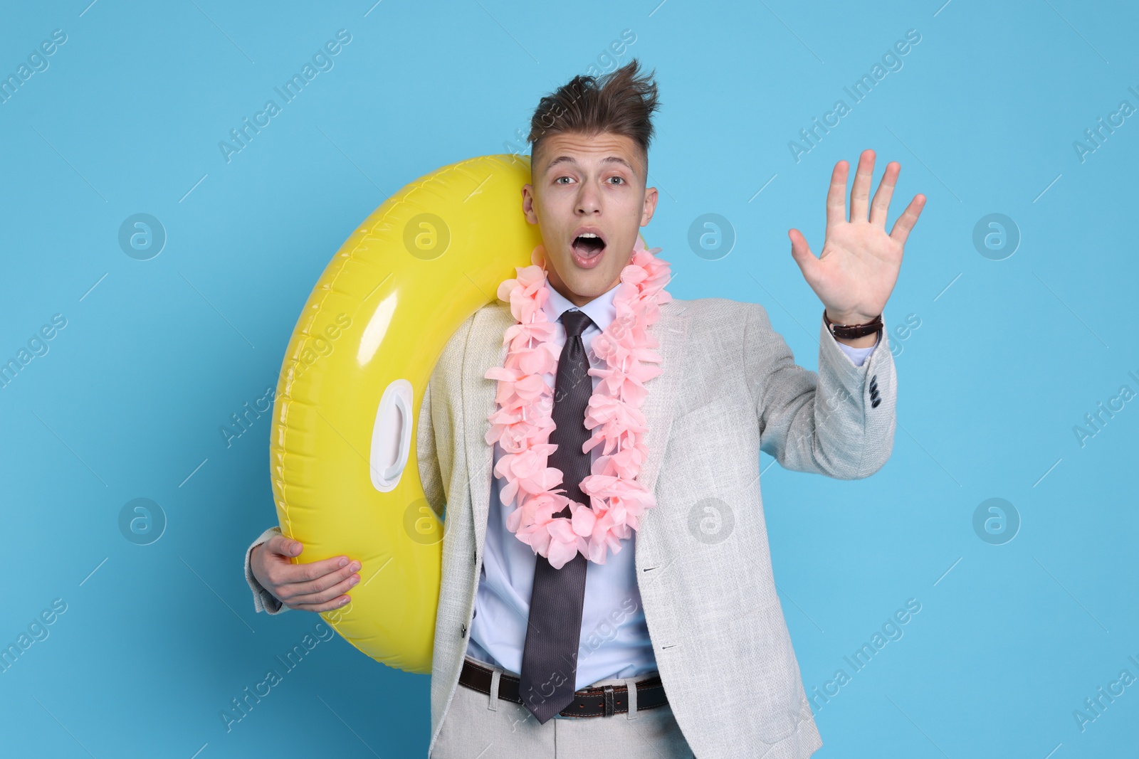 Photo of Businessman with inflatable ring and wreath of flowers on light blue background