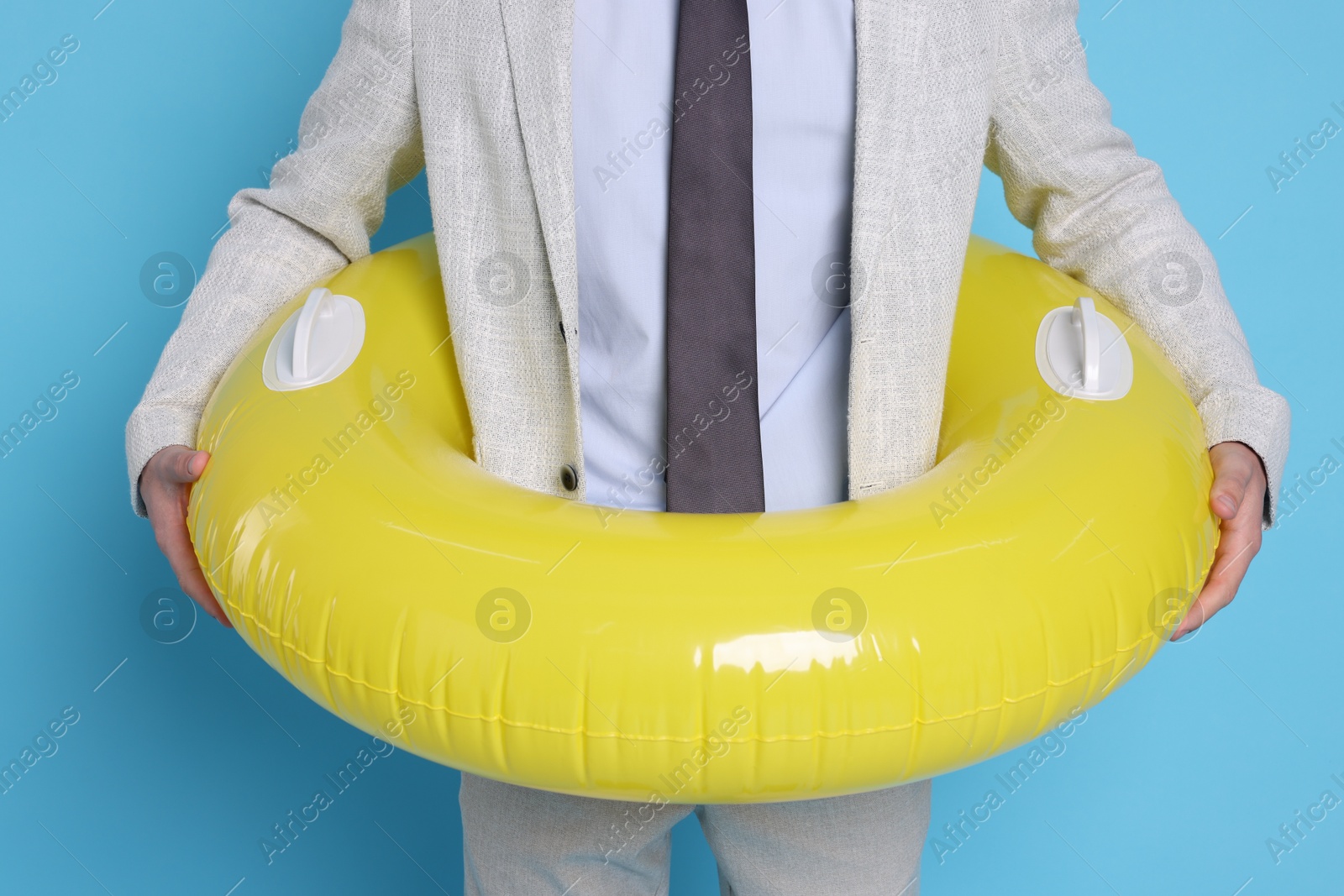 Photo of Businessman with inflatable ring on light blue background, closeup