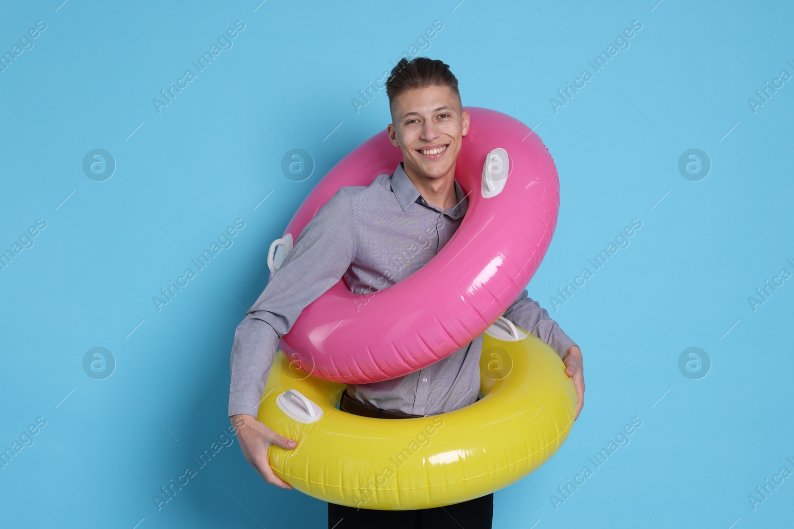 Photo of Businessman with inflatable rings on light blue background