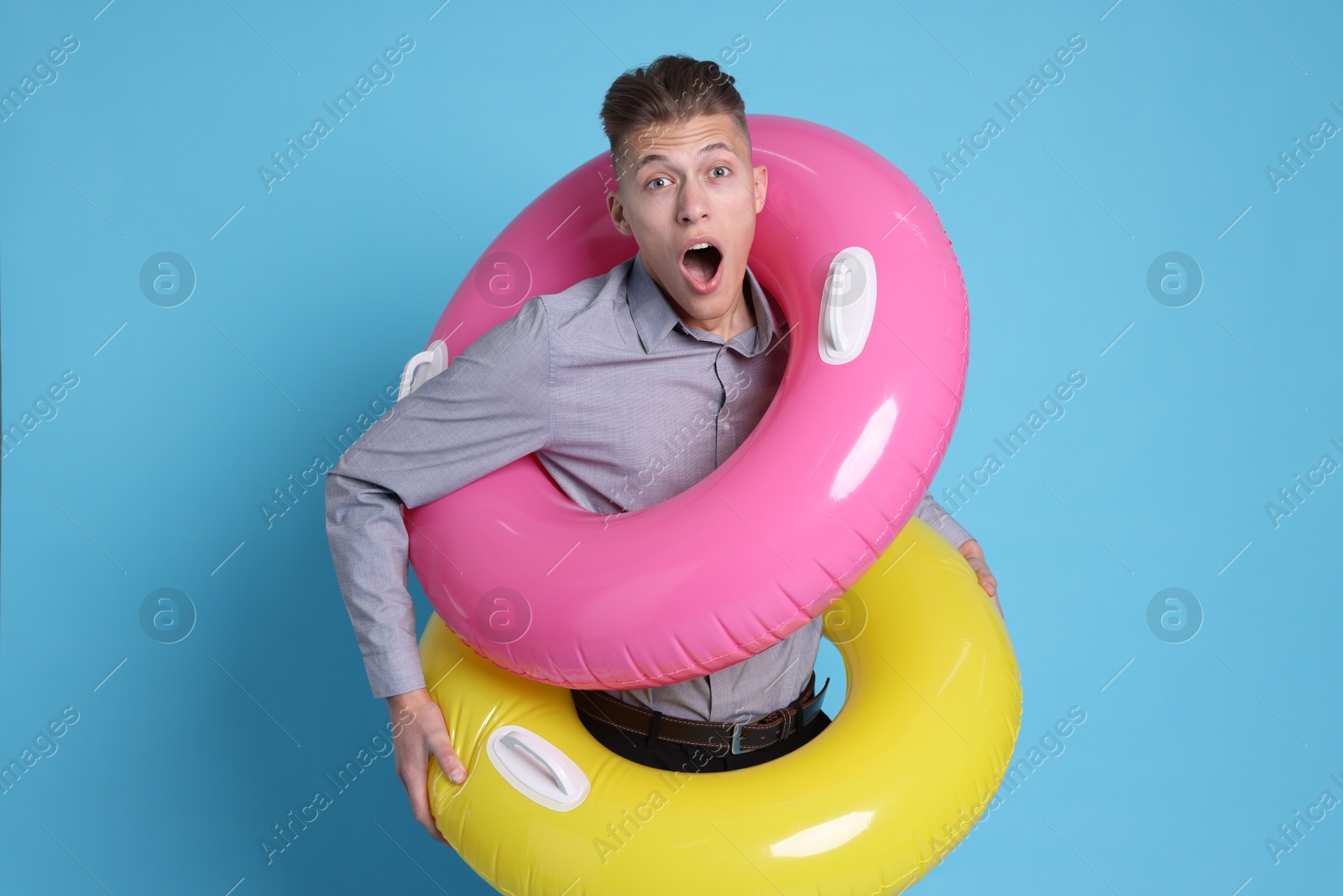 Photo of Businessman with inflatable rings on light blue background