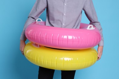 Photo of Businessman with inflatable rings on light blue background, closeup