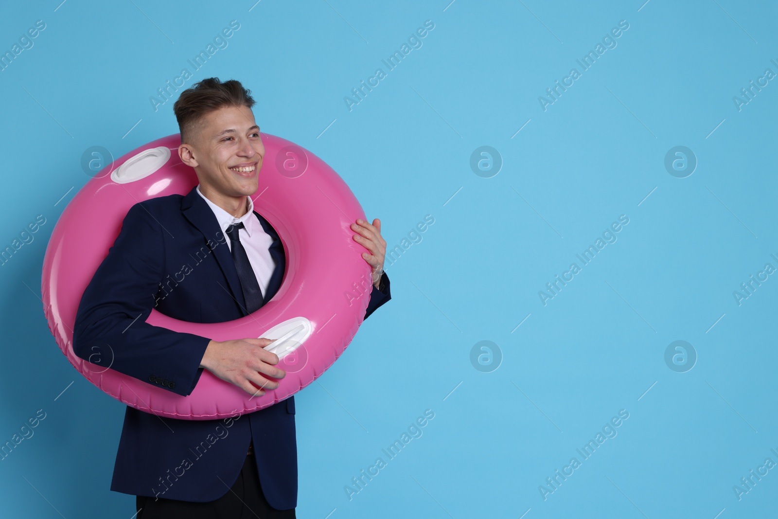 Photo of Businessman with inflatable ring on light blue background, space for text