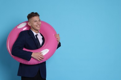 Photo of Businessman with inflatable ring on light blue background, space for text