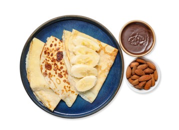 Photo of Delicious crepes with chocolate sauce, banana and almonds isolated on white, top view