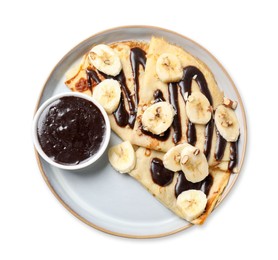 Photo of Delicious crepes with chocolate sauce, banana and almonds isolated on white, top view