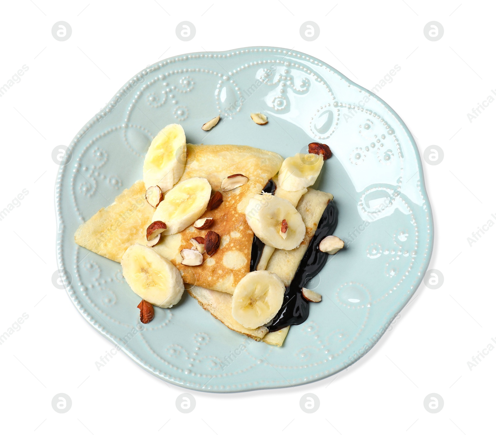 Photo of Delicious crepes with banana, chocolate sauce and nuts isolated on white, top view