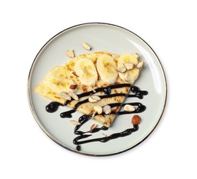 Photo of Delicious crepe with banana, nuts and chocolate sauce isolated on white, top view