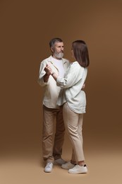 Photo of Father dancing with his daughter on brown background