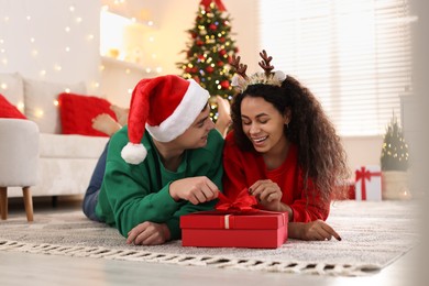 Photo of Happy couple with Christmas gift spending time together at home