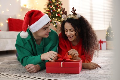 Photo of Happy couple with Christmas gift spending time together at home