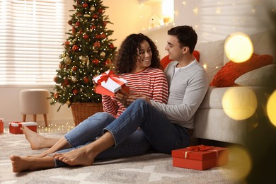 Photo of Happy couple with Christmas gifts spending time together at home