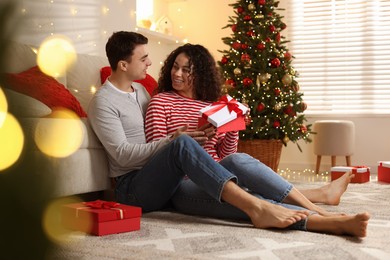 Photo of Happy couple with Christmas gifts spending time together at home