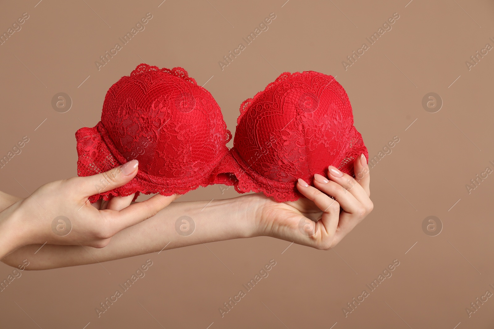 Photo of Woman holding red bra on dark beige background, closeup