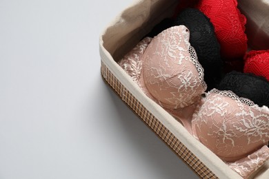 Photo of Beautiful bras in basket on light background, above view. Space for text