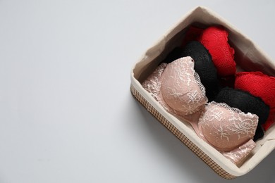 Photo of Beautiful bras in basket on light background, top view. Space for text