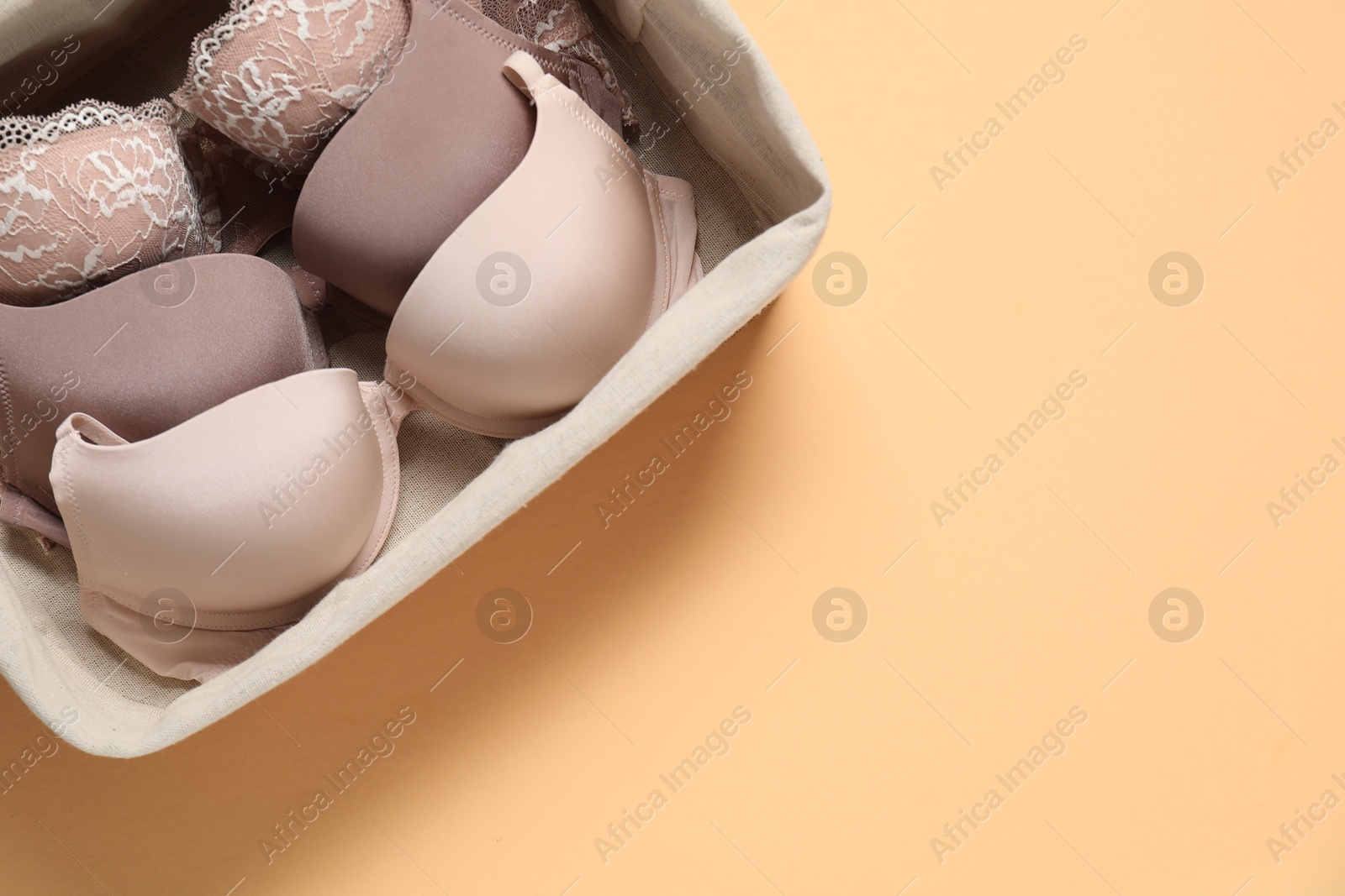 Photo of Beautiful bras in basket on beige background, top view. Space for text