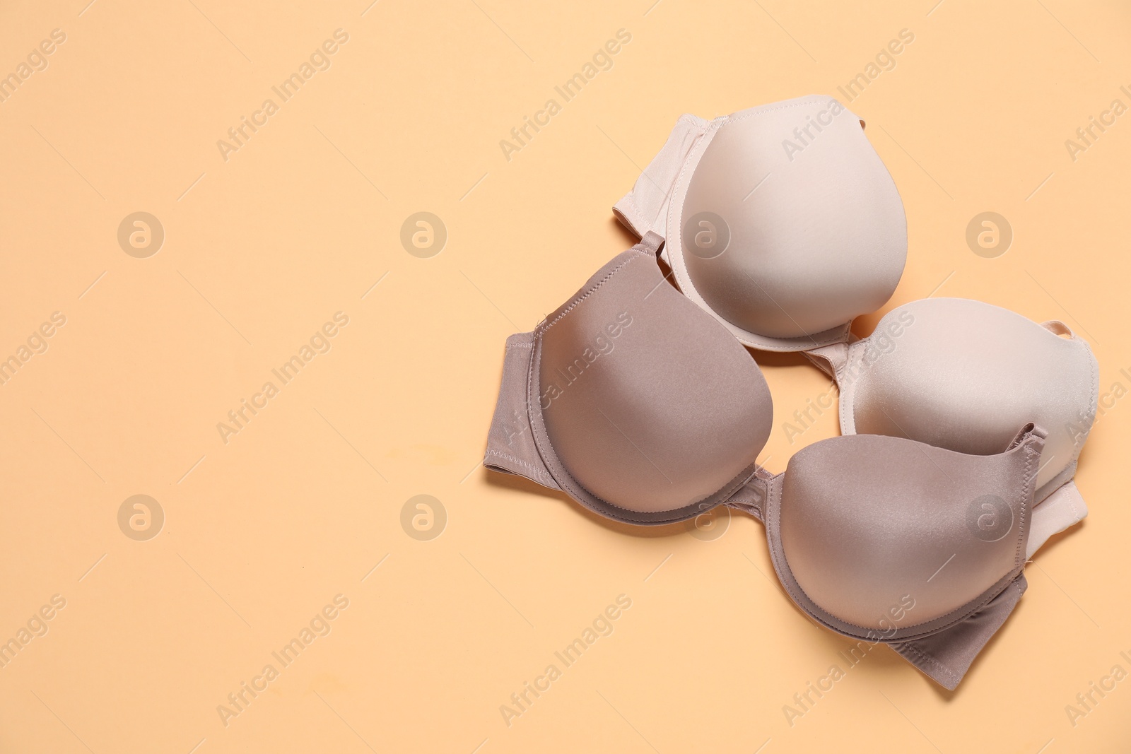 Photo of Beautiful bras on beige background, flat lay. Space for text