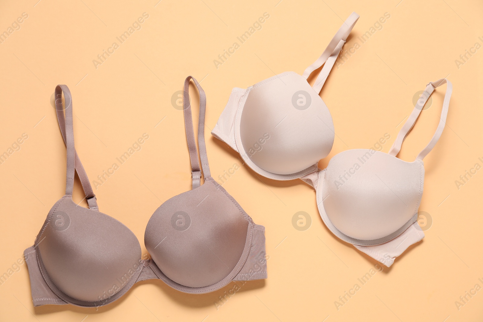 Photo of Beautiful bras on beige background, flat lay