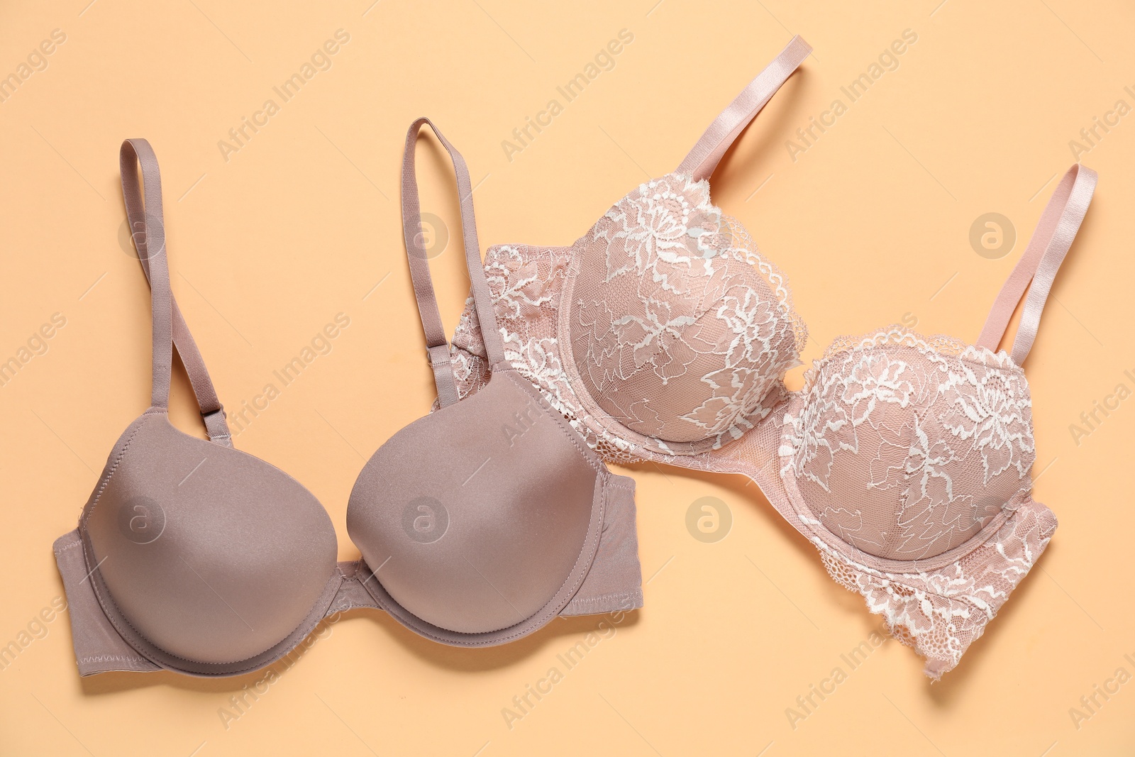 Photo of Beautiful bras on beige background, flat lay