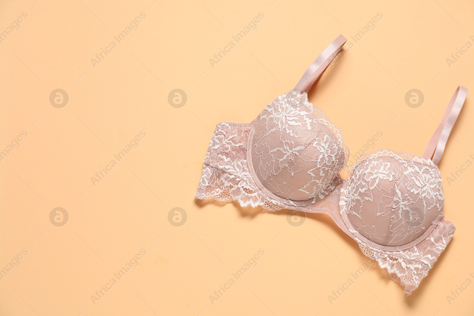 Photo of Beautiful lace bra on beige background, top view. Space for text