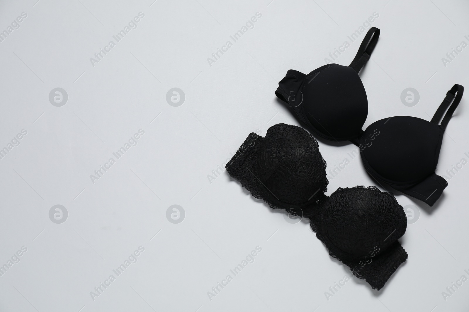 Photo of Beautiful black bras on white background, flat lay. Space for text