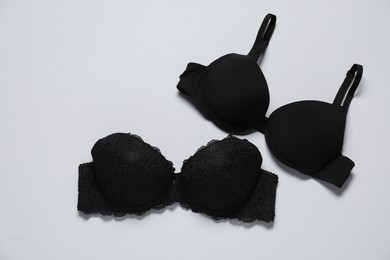 Photo of Beautiful black bras on white background, flat lay