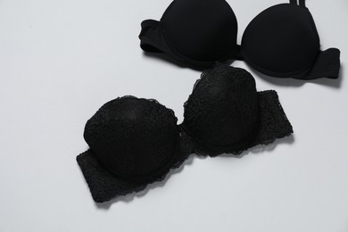 Photo of Beautiful black bras on white background, flat lay