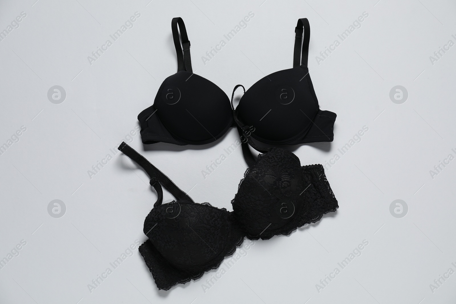 Photo of Beautiful black bras on white background, flat lay