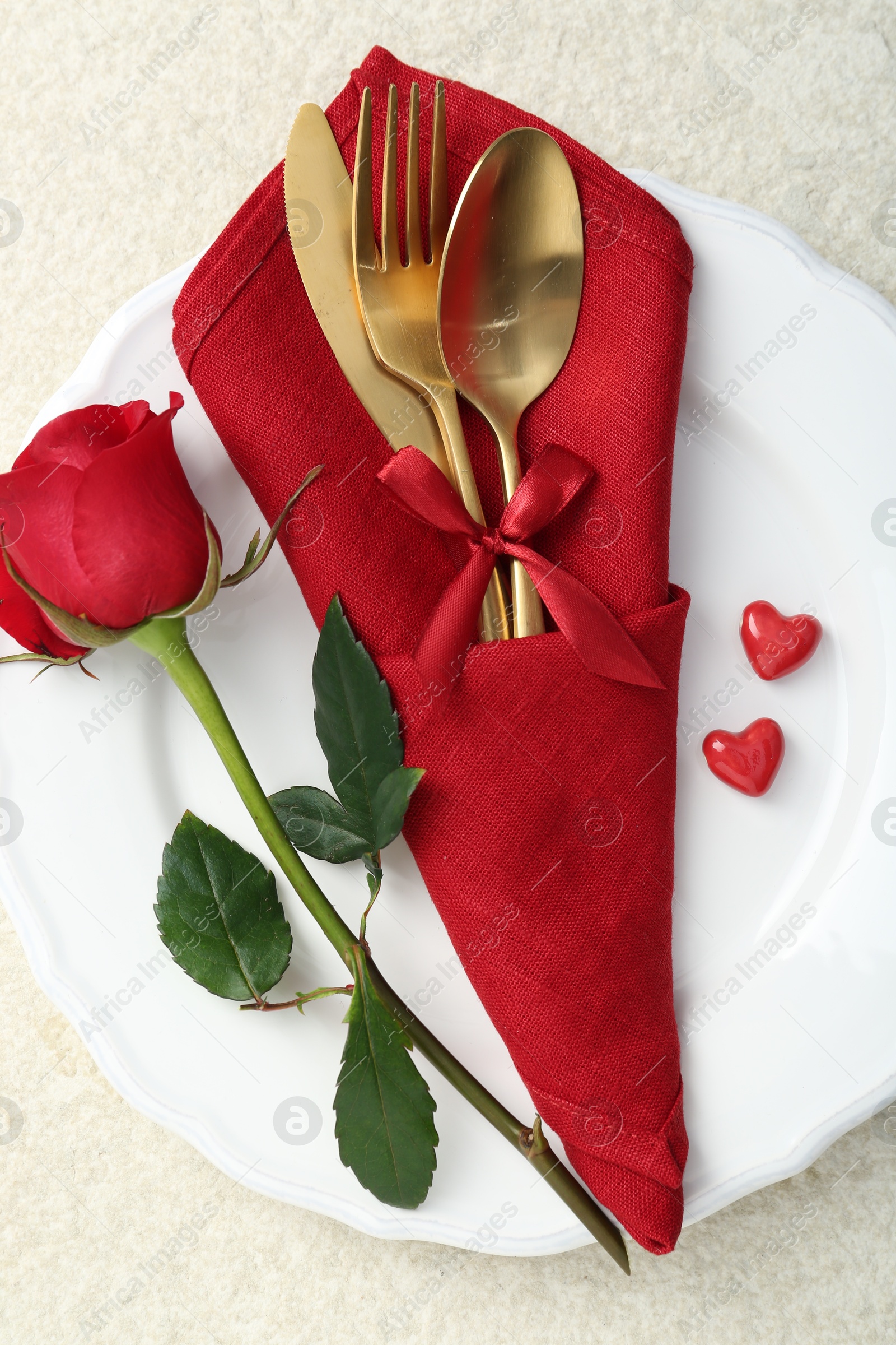 Photo of Romantic place setting with red rose on white table, top view. Valentine's day celebration