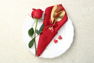 Photo of Romantic place setting with red rose on white table, top view. Valentine's day celebration