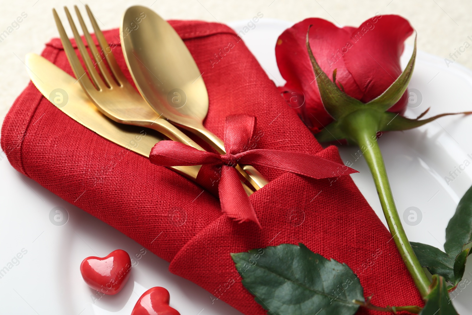 Photo of Romantic place setting with red rose on white table, closeup. Valentine's day celebration