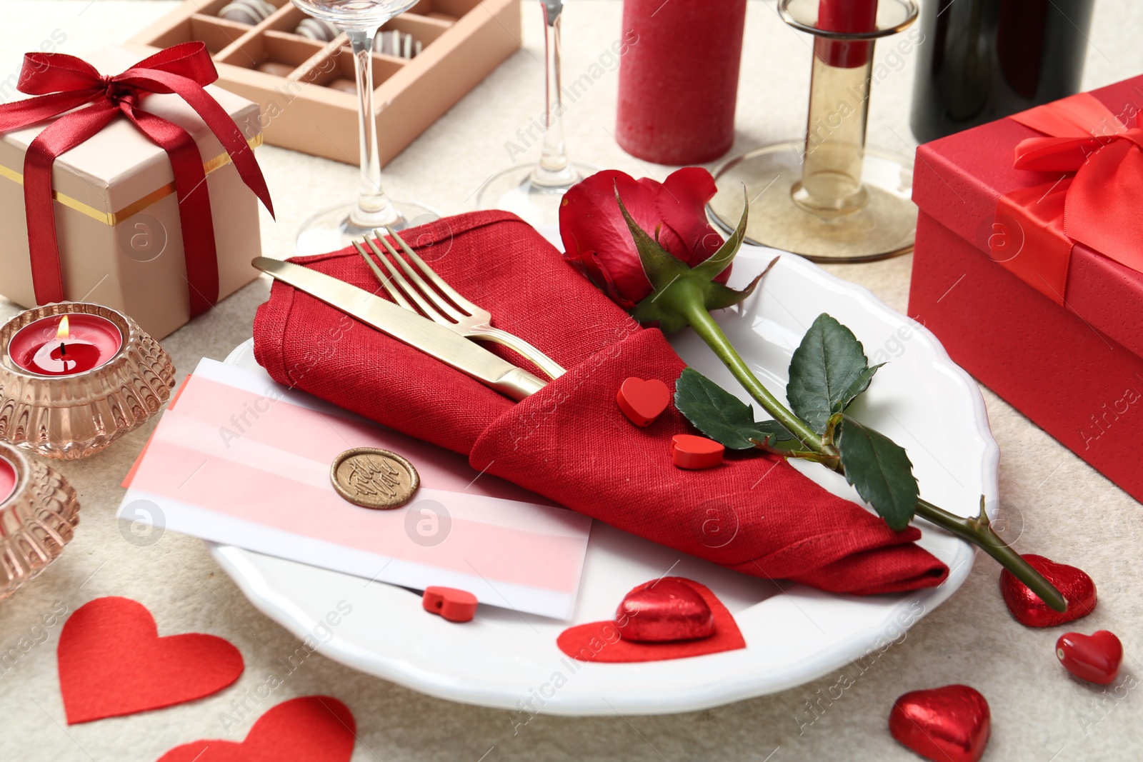 Photo of Romantic place setting with red rose on table, closeup. Valentine's day celebration