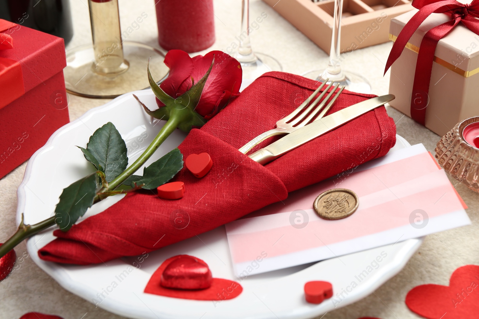 Photo of Romantic place setting with red rose on table, closeup. Valentine's day celebration