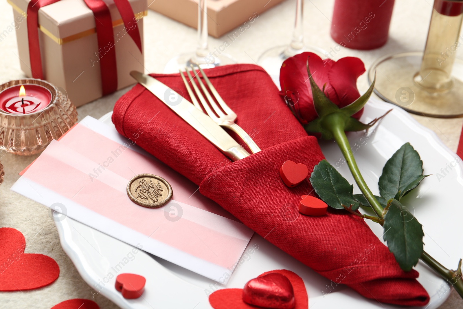 Photo of Romantic place setting with red rose on table, closeup. Valentine's day celebration