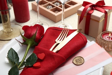 Photo of Romantic place setting with red rose on table, closeup. Valentine's day celebration