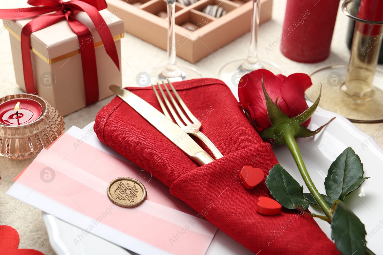 Photo of Romantic place setting with red rose on table, closeup. Valentine's day celebration