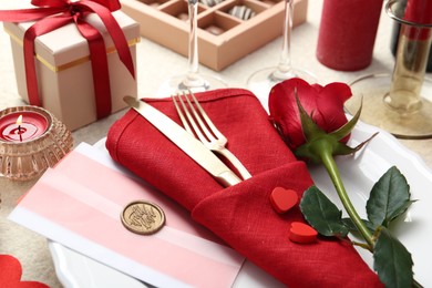 Photo of Romantic place setting with red rose on table, closeup. Valentine's day celebration