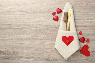 Photo of Romantic place setting with cutlery and hearts on wooden table, top view. Valentine's day celebration