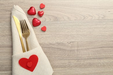 Photo of Romantic place setting with cutlery and hearts on wooden table, top view. Valentine's day celebration