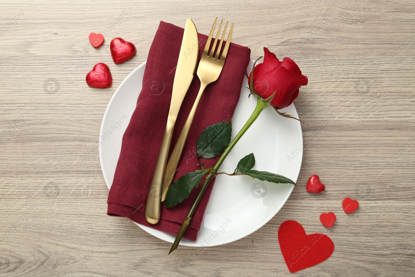 Photo of Romantic place setting with red rose on wooden table, top view. Valentine's day celebration